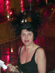 Woman facing the camera, wearing a low-cut top and elaborate feathered hat