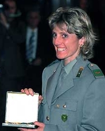 Photographie d'une femme souriante en tenue militaire tenant un coffret dans ses mains.