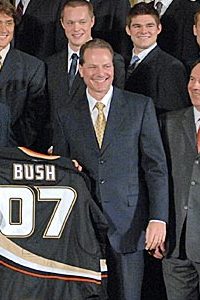 Samueli wearing a black suit presenting a black hockey jersey labeled "Bush 07" to President George W. Bush.