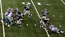 A quarterback is shown in the process of throwing a forward pass. His offensive linemen are in front of him.