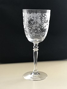 elegant stemmed wine glass with etching that appears to be plant-like