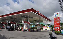 Low angle shot of a large canopy over fuel pumps on a sunny day against a white-clouded sky