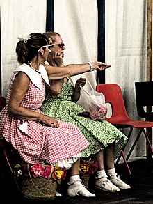 Two women seated in typical teen girl fashion from the 1950s, wearing bobby socks