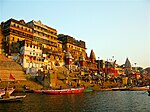 Ganges riverfront with steps, temples, people, and boats