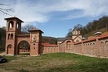 Monasterio de Bešenovo, un edificio de ladrillo rojo con una entrada arqueada y una torre
