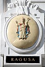 Das alte Wappen von Dubrovnik mit dem Stadtpatron St. Blasius auf dem einst von der Marinesektion des k.u.k. Kriegsministeriums genutzten Amtsgebäude Marxergasse 2 in Wien. Im amtlichen Gebrauch der k.u.k. Marine wurden die Namen in italienischer Sprache verwendet.