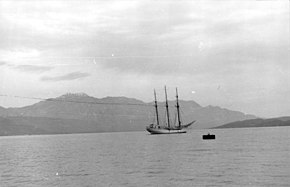 A black and white photograph of a sailing ship in a bay