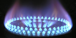 Close-up image of a natural gas burner on a stove showing the characteristic blue hue of a natural gas flame.