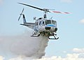 Bell 205 d'un departamentu de quemes de California llanzando agua sobre un fueu.