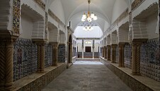 A long hallway lined with pillars and decorated in patterned tile