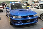 Subaru Impreza 22B-STI Version, a high-performance variant of the standard Subaru Impreza coupe. This photo shows the front of the car, which is blue with gold-colored wheels and a pink Subaru emblem.