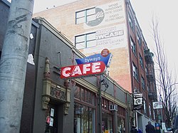 Photograph of a building's exterior, with a neon sign