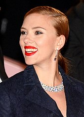 Scarlett Johansson, wearing a dark blue coat, smiles to her left.