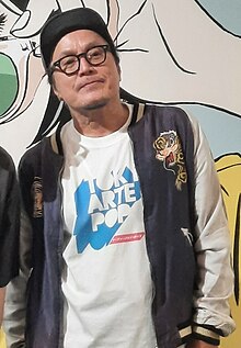 Hisashi Eguchi standing in a convention