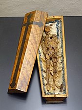 Memento mori in die vorm van 'n klein kis, 1700's, wasfiguur op satyn in 'n houtkis (Museum Schnütgen, Keulen, Duitsland)
