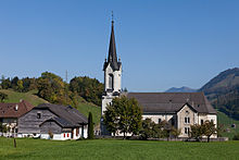 A church with a high steeple on a green field