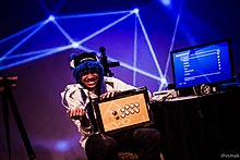 SonicFox holding his Evo 2015 trophy and arcade stick.