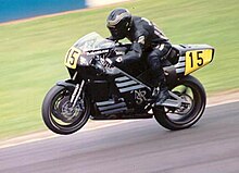 Black motorcycle racing at a non-street circuit with rider also wearing black