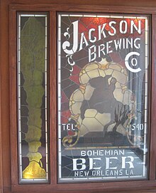 Stained glass panel with the silhouette of a man on a rearing horse and lettering for "Jackson Brewing Co."