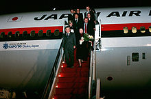 Japan Prime Minister Noboru Takeshita and 11 others deplane on steps in red color, from a Japan Air Lines DC-10 marked with an Official Airline for Expo '90 Osaka, Japan logo and text