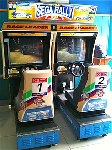 An arcade cabinet with two seats and steering wheels