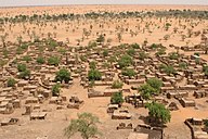 Pasir gurun melitupi satu kampung yang terdiri daripada rumah kecil yang berbumbung rata dengan beberapa pokok hijau di sekitarnya
