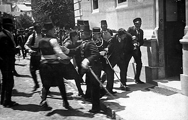 Group of gendarmes dragging a man towards a building.