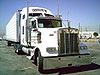 A large gleaming white truck faces diagonally right towards the camera.