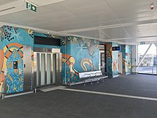 Lift entrance with teal and orange painted artwork along the wall
