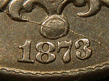 A closeup of part of an 1873 Shield nickel, showing the date, in which the arms of the "3" reach close to each other