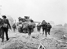 Soldados britânicos avançando em direção de Ouistreham, apoiados por blindados.