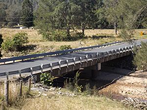 Low set concrete beam and girder bridge with asphalt carriage way surface and steel side safety rails.
