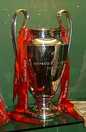 A silver trophy with red ribbons on it
