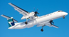 WestJet Encore Q400 in flight with propellers turning and landing gear extended