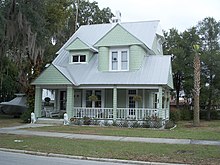 a green two story house with shingles