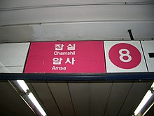 An overhead sign in rose and white with a big number 8 and the words Chamshil and Amsa in hangul and Latin script.