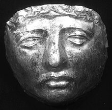Black and white photograph of a gold death mask resembling a human face