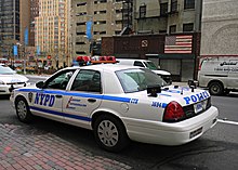 a parked NYPD crown victoria passenger vehicle with license plate readers mounted on either side of the rear bumper.