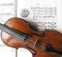 photographie montrant un violon aux cordes croisées, à l'arrière-plan une partition