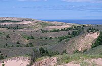 Sandy dunes with shrubs and Lake Superior in background