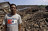 Seorang pria dengan latar belakang rumah hancur di Bantul