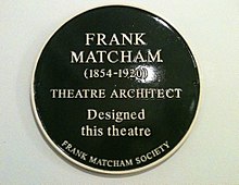 A dark green, circular plaque with the words "Frank Matcham (1854–1920) Theatre Architect Designed this theatre The Frank Matcham Society" in gold lettering.