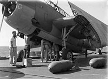 Black and white photograph of an aircraft being loaded with bombs