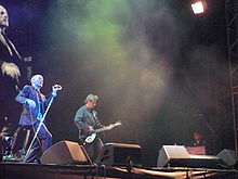R.E.M. performing onstage, with Michael Stipe singing, Peter Buck playing guitar, and Scott McCaughey playing keyboards