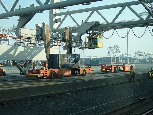 Onbemand voertuig (AGV - Automatic Guided Vehicle) waarop een containerkraan bijECT containers overlaadt van een schip.