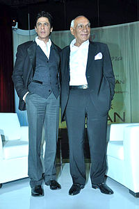 Shahrukh Khan and Yash Chopra are looking away from camera.