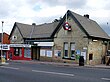 A beige-bricked building with a rectangular, dark blue sign reading "TOTTERIDGE & WHETSTONE STATION" in white letters all under a blue sky