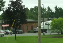 A view of the G. Stone Motors dealership building in Middlebury, Vermont, taken from U.S. Route 7 in Vermont, with some trees and a telephone pole in the foreground