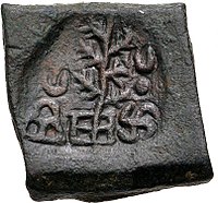 A coin of Takshashila, portrays a tree flanked by a hill surmounted by a crescent and a Nandipada above a swastika.[27]