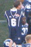Connecticut Huskies football uniform with number 6 held up by another uniformed player on the sideline